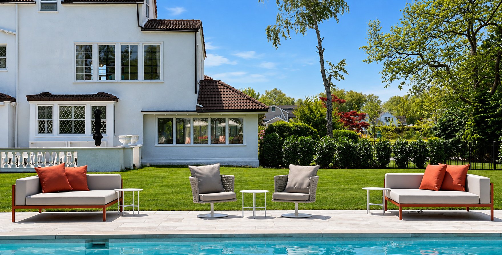 Cream sofas with terracotta cushions on a lawn beside a pool