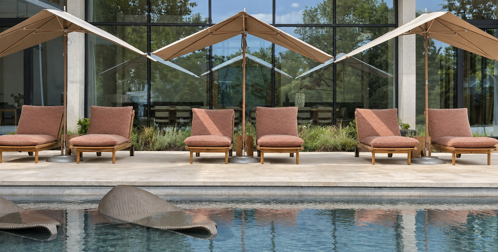 Six teak loungers under cantilever parasols beside a reflecting pool