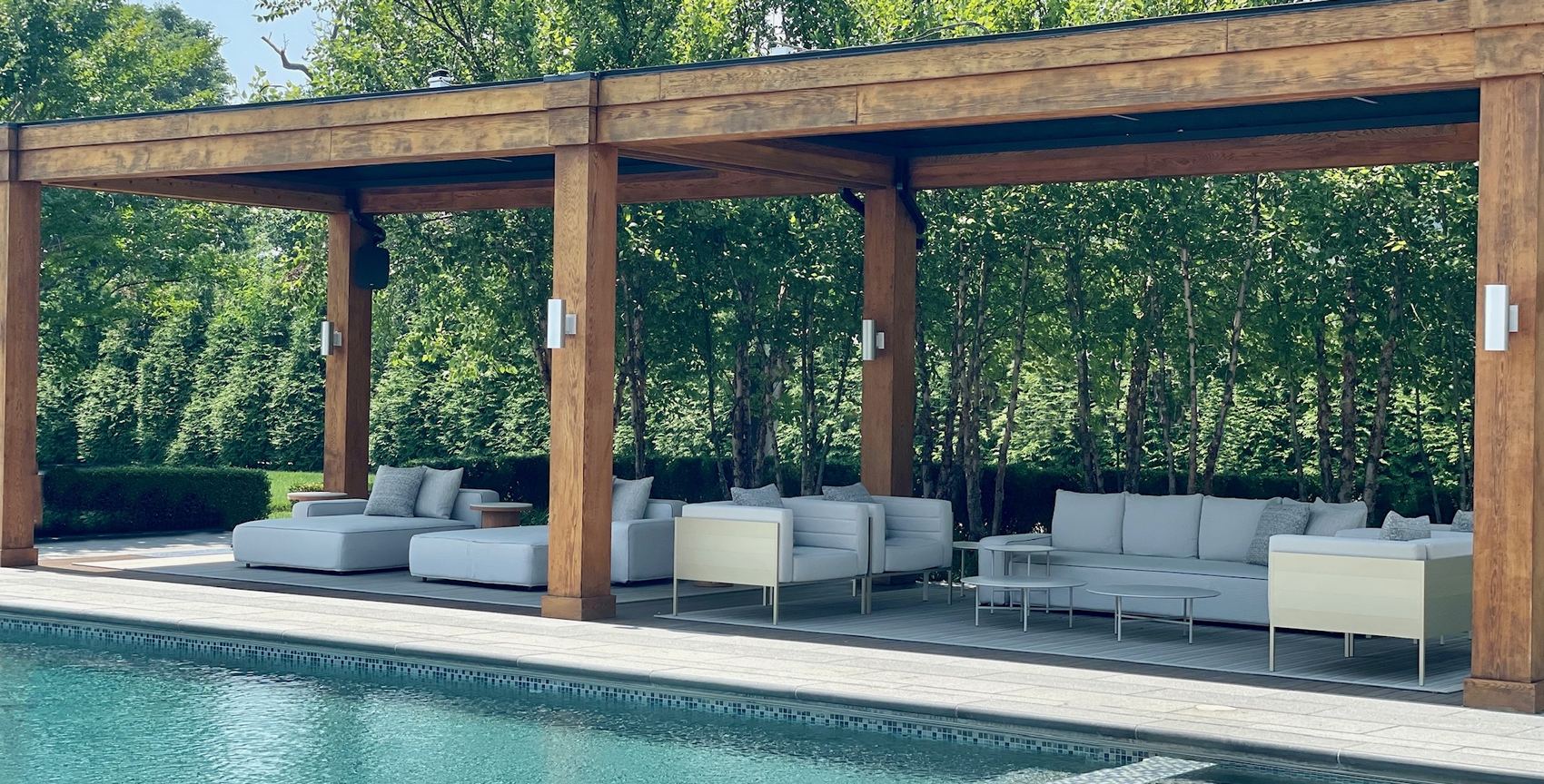 A timber pergola over lounge seating beside a long pool