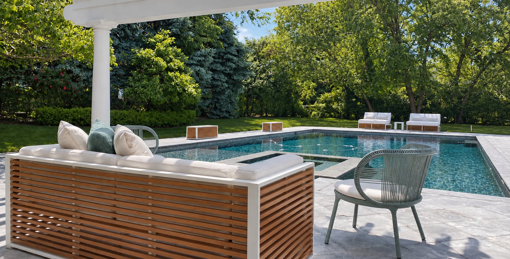 A slatted teak sofa under a white pergola beside the pool, with lounge seating on the far side