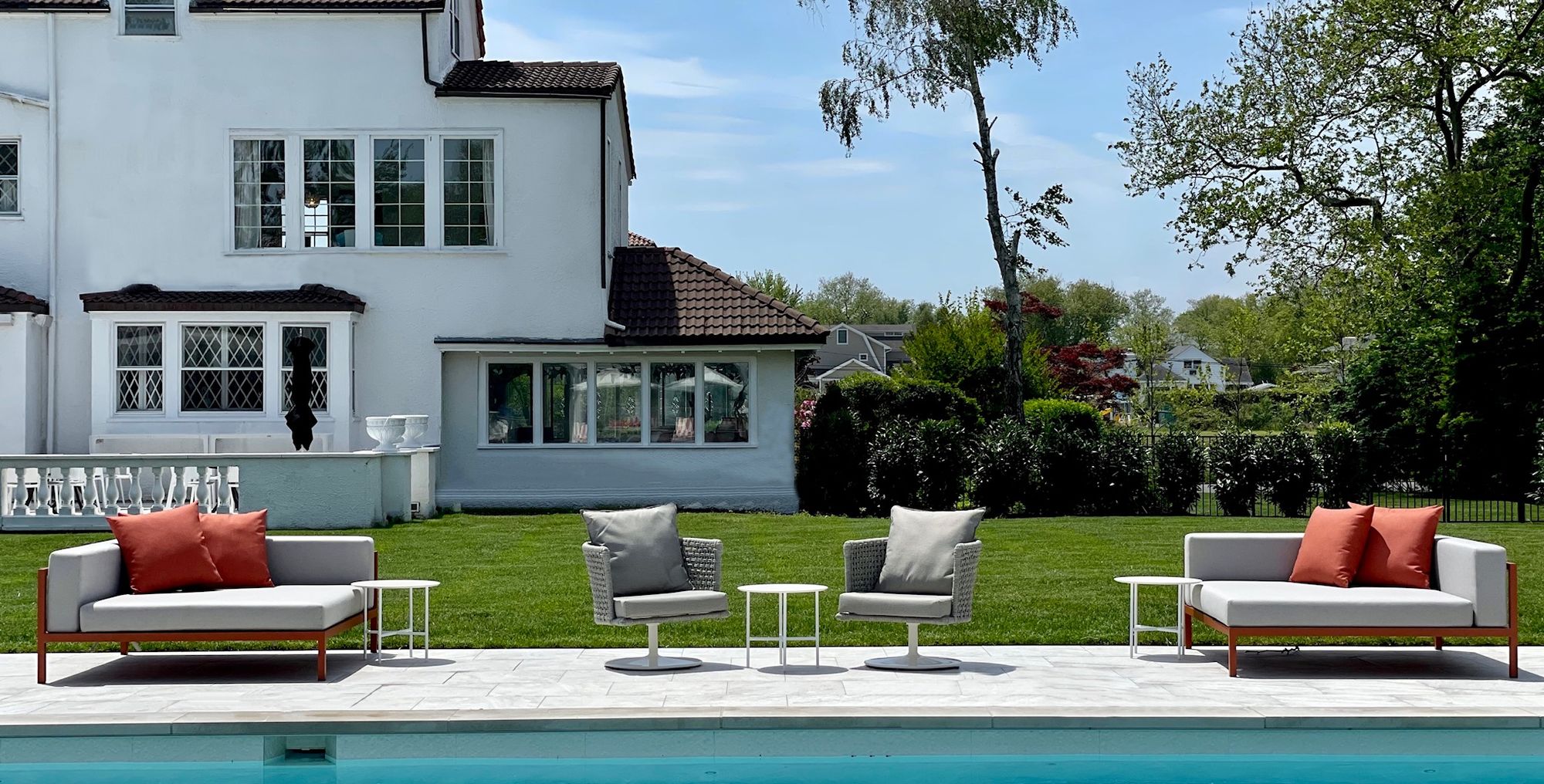 Sofas and low tables set out on the lawn beside a pool