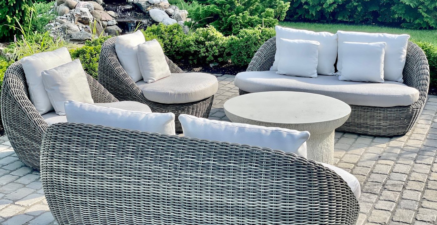 Woven daybeds and curved seating around a low table on a stone terrace